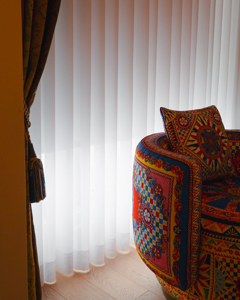 Close view of white sheer folds and hems beside an armchair