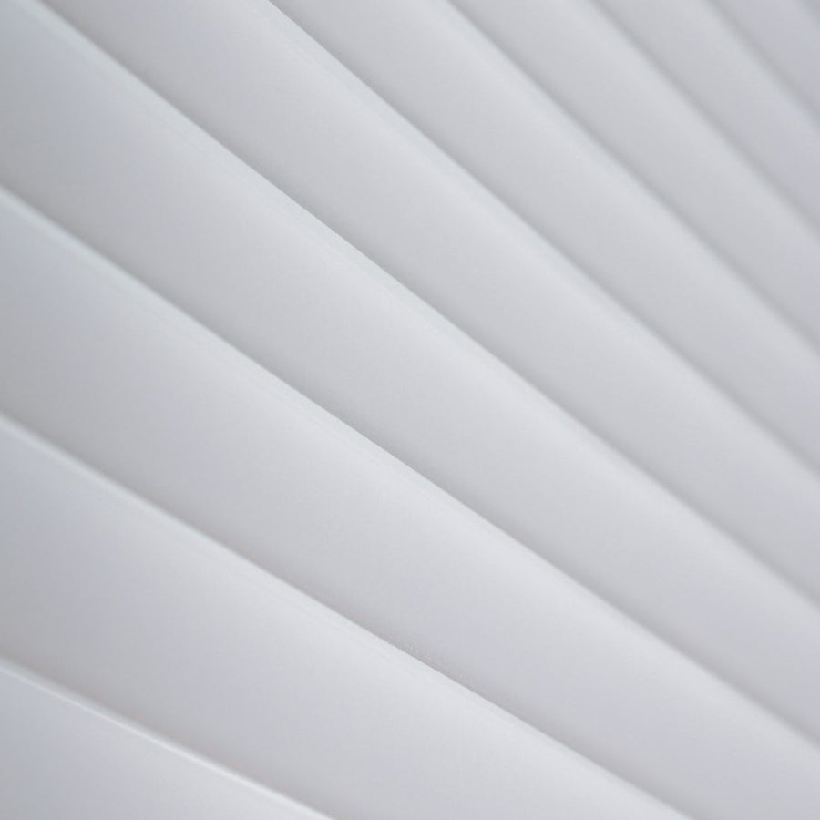 Detail of the folds of a white shade lit from the side, each fold casting its own shadow